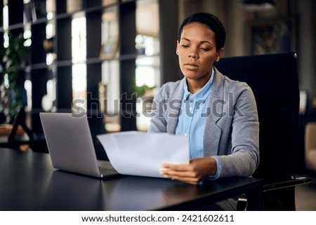 Focused African businesswoman reading some documents at the office.
