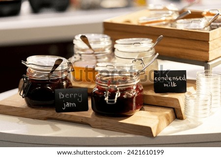 close-up breakfast buffet line serving a variety of jams in hotel with hospitality signs