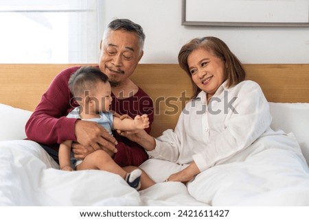 Portrait of happy love asian grandfather with grandmother playing with asian baby on bed, senior, insurance.Big family love with their laughing grandparents smiling together.Family and togetherness