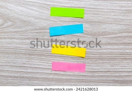 Four colored markers on a wooden table. Colorful post paper notes or bookmarks on gray background. Journaling and office desk concept