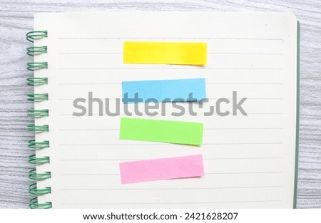Five colored markers in a notebook on a wooden table. Colorful post paper notes or bookmarks on gray background. Journaling and office desk concept