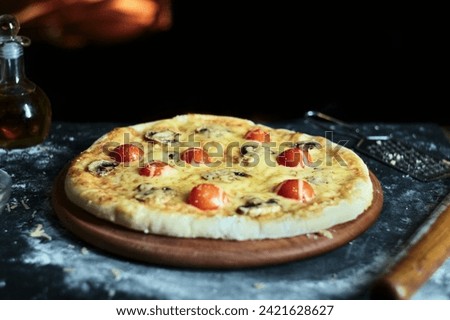 Pizza with mushrooms and tomatoes with cheese on the background of the oven.