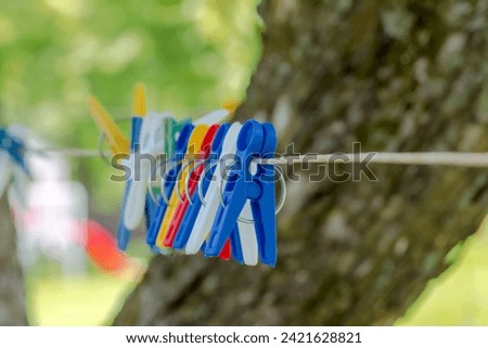 Colorful clothespins hanging on a laundry drying line. Plastic clothespins in different colors for washing - hanging on a line .