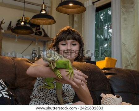 Wild animal in human hands. The girl smiles and holds an iguana in her hands