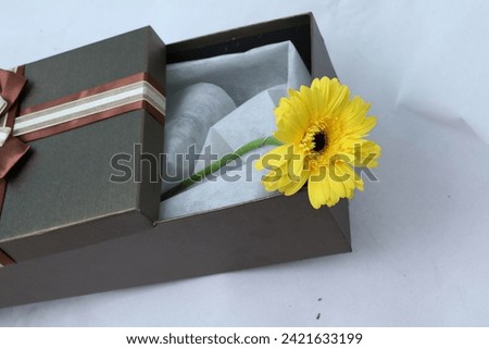 Gift or present box and flowers on white table from above, flat lay frame