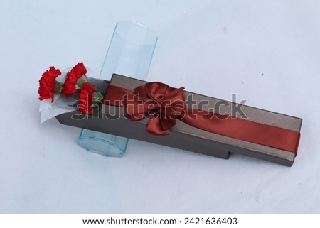 Gift or present box and flowers on white table from above, flat lay frame