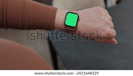 Woman use modern smartwatch with a green screen chromakey. Wearable technology device closeup. Mock-up for tracking.