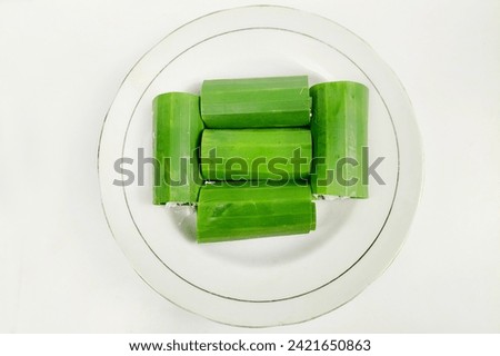White rice cake wrapped in banana leaves on a plate