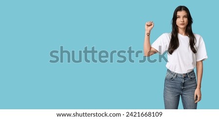 Young woman showing female gender symbol on her wrist against blue background with space for text. Feminism concept