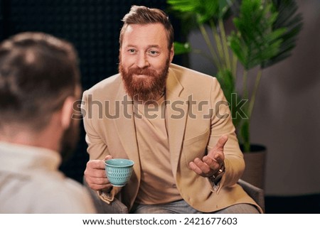 cheerful men in fashionable clothing sitting with coffee cup and discussing interview questions