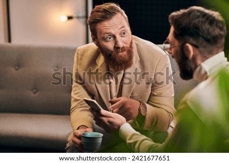 handsome bearded man talking to his interviewer in glasses that holding smartphone during discussion