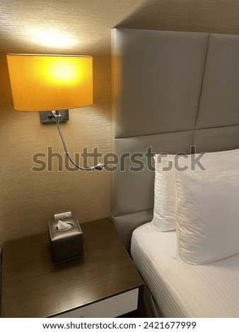 Side table and lamp beside a comfort bed with white pillows Royalty-Free Stock Photo #2421677999