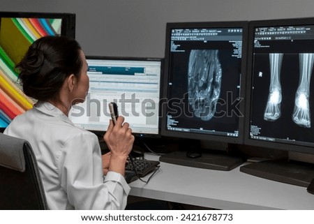 radiology doctor examines foot, ankle x-ray, mr image and reports with microphone looking computer screen, X-ray analysis room reading X-rays of a heel, toe and other parts of the body.	 Royalty-Free Stock Photo #2421678773