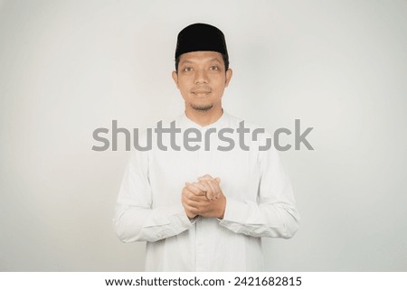 Happy smiling Asian Muslim man in Arabic costume standing with Eid greeting gesture and welcoming Ramadan isolated background