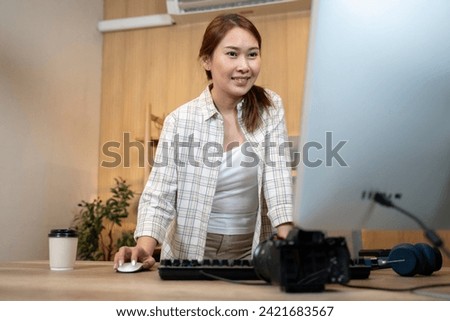 Happy female video editor works indoors in creative office studio. Royalty-Free Stock Photo #2421683567