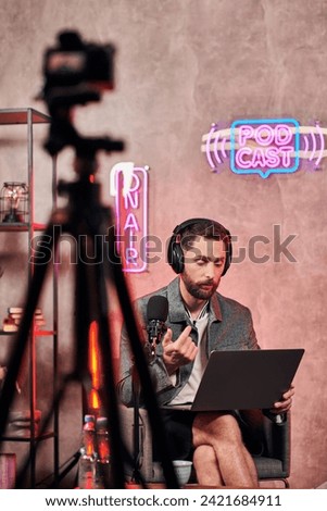 good looking bearded man in casual comfy attire sitting with laptop during podcast in studio