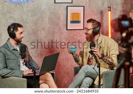 cheerful men in comfortable attires with coffee and laptop during their discussion on podcast