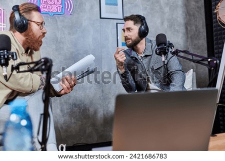 good looking stylish men with beards and headphones discussing questions in studio during podcast