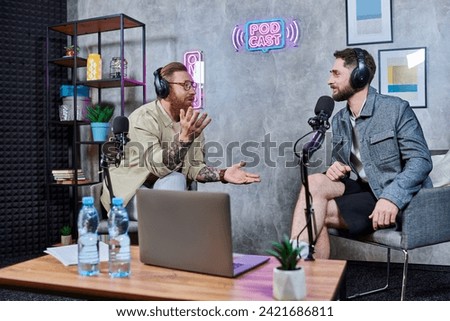 good looking interviewer and his guest with headphones in studio discussing questions, podcast