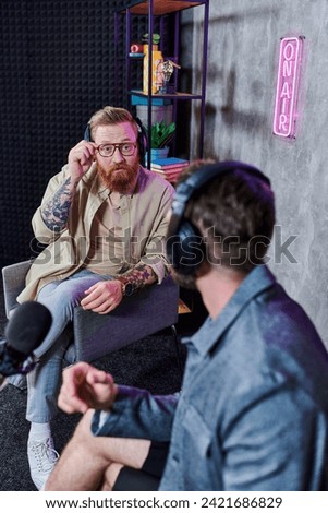 handsome interviewer with red hair and his guest with headphones discussing questions, podcast