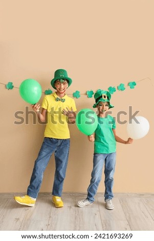 Funny kids with face paintings and balloons near beige wall. St. Patrick's Day celebration