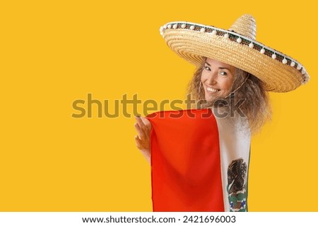 Mature woman in sombrero hat with flag on yellow background. Mexico's Day of the Dead (El Dia de Muertos) celebration Royalty-Free Stock Photo #2421696003