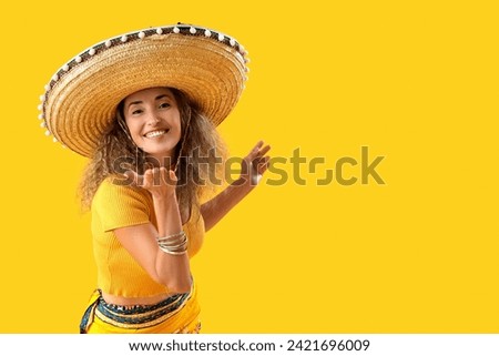 Mature woman in sombrero hat on yellow background. Mexico's Day of the Dead (El Dia de Muertos) celebration Royalty-Free Stock Photo #2421696009