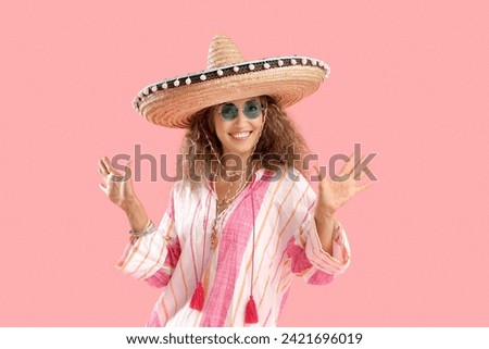 Mature woman in sombrero hat on pink background. Mexico's Day of the Dead (El Dia de Muertos) celebration Royalty-Free Stock Photo #2421696019