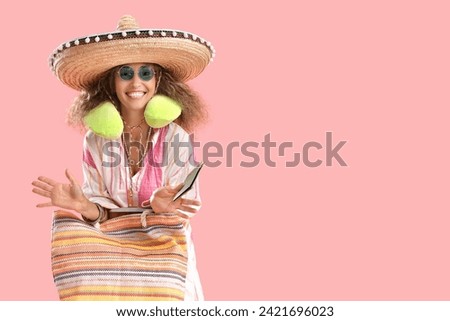 Mature woman in sombrero hat with passport and bag on pink background. Mexico's Day of the Dead (El Dia de Muertos) celebration Royalty-Free Stock Photo #2421696023