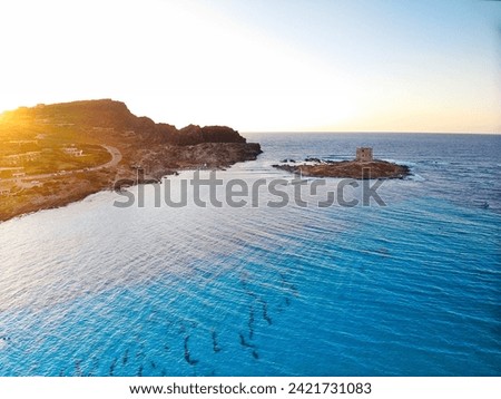 Aerial shot of Caletta della Torre islet by La Pelosa Beach, Sassari, Sardinia. Well-preserved ruins of Torre della Pelosa tower, formerly a prison. Royalty-Free Stock Photo #2421731083