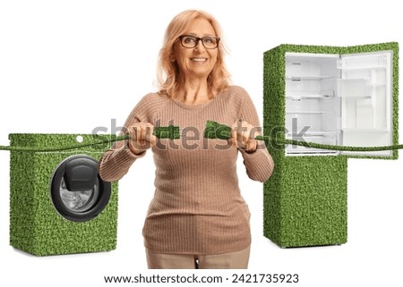 Woman plugging in green electric cables in front of power efficient home appliances isolated on white background Royalty-Free Stock Photo #2421735923