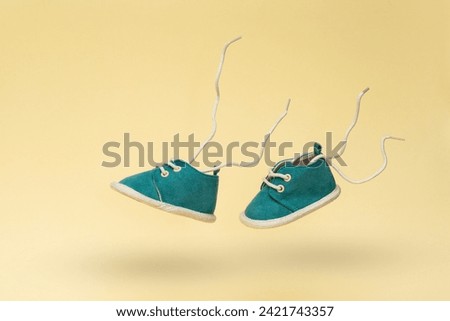 Flying baby shoes with flying laces on yellow background. Newborn baby concept with levitation effect and copy space Royalty-Free Stock Photo #2421743357