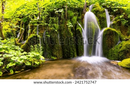 Cascade panorama at Plitvice Lakes or “Plitvička jezera“ National Park in Croatia with bright green vegetation. Pool and waterfall in natural reserve and tourist attraction with longtime exposure. Royalty-Free Stock Photo #2421752747