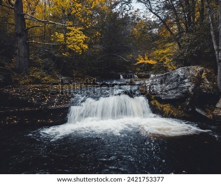 A magnificent fall waterfall on a fast-moving River in the forest