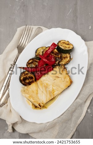 Fish dish - fried cod fish with grilled vegetables in white plate