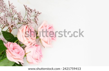 Rose fresh flowers with leaves frame on table from above with copy space