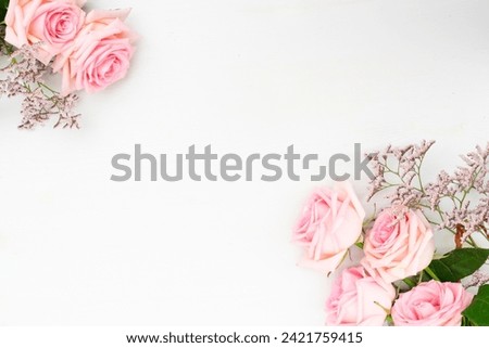 Rose fresh flowers with leaves frame on table with copy space, flat lay scene