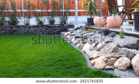 ornamental garden of a family house, living fence, wooden fencing, stone wall Royalty-Free Stock Photo #2421761835