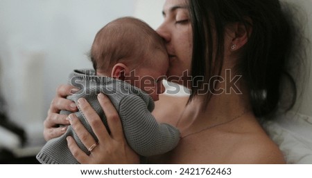 Candid mother holding newborn baby in bed showing love care and affection Royalty-Free Stock Photo #2421762463
