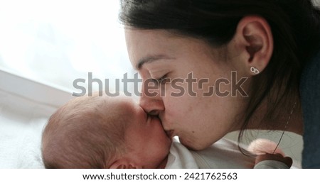 Mom kissing newborn baby son in the cheek