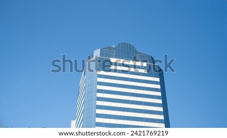 Modern skyscrapers with reflective glass facades against a clear blue sky with flying birds in Jacksonville, Florida.
