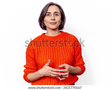Attractive cheerful darkhaired woman smiling. Orange knitted warm sweater. Hands in front of chest. Royalty-Free Stock Photo #2421770167