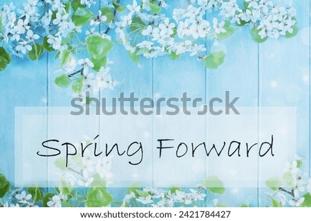 Spring forward sign over a beautiful spring tree blossoms against a peaceful blue rustic wooden background. Image shot from above in flat lay table top view. 