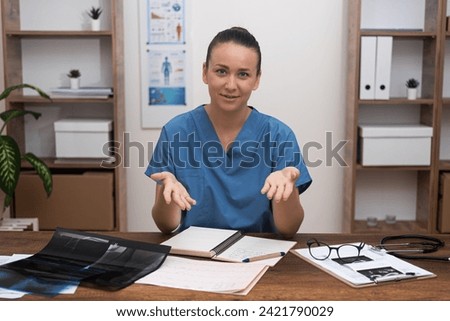 Doctor tells information to patient sitting at table with pictures of examinations in office practitioner gives advice on treatment explaining specifics of disease