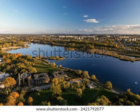 Aerial view of Bagry lake and autumn forest in Poland. Amazing panoramic landscape with waters of spectacular Bagry lagoon and road along beach, houses of town and scenic tops of trees under blue sky Royalty-Free Stock Photo #2421792077