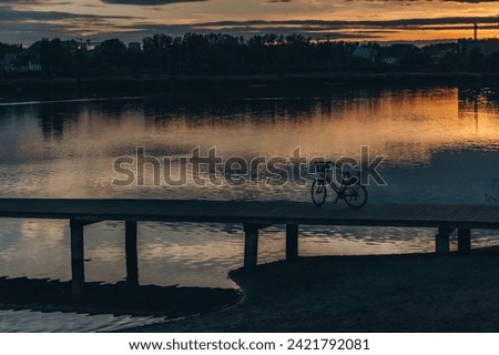 Empty Bagry lake wooden pier with bicycle in parking lot at sunset, Poland