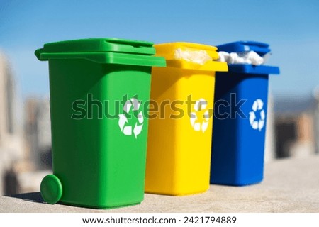 Container trash bin for recycling with city background. Yellow, green, blue bins for recycle plastic, paper and glass trash. Environmental awareness, recycling, waste management concept.
