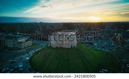 Aerial view of a historic castle at sunset with surrounding cityscape and dramatic sky in York, North Yorkshire