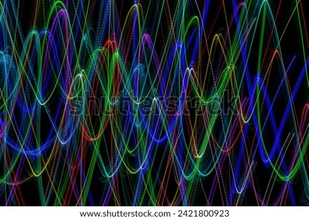 Multi-colored lines in the shape of waves on a black background. Long exposure photography
