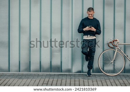young man with bicycle and mobile phone with street wall background and copy-space